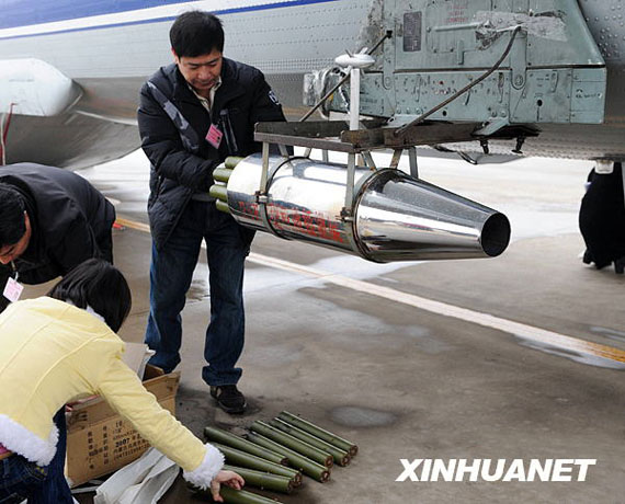 資料圖：2月8日，在河南省鄭州市新鄭機(jī)場，工作人員往飛機(jī)上裝掛人工增雨用的碘化銀催化劑。